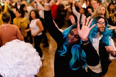 People in fun wigs dancing at a party.