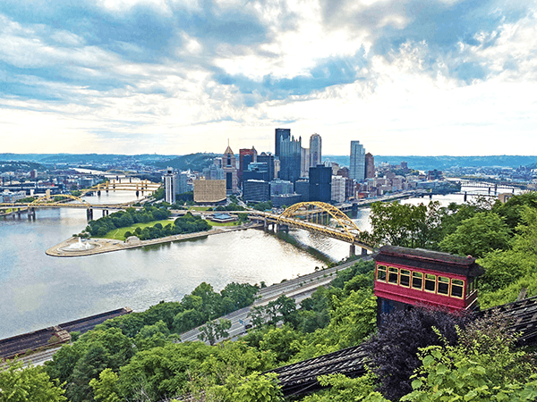 View of Pittsburgh from a hilltop with trees and classic funicular in the foreground