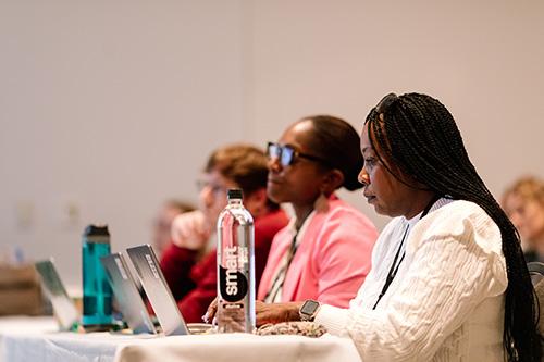 two people looking at their laptop screens during a conference session
