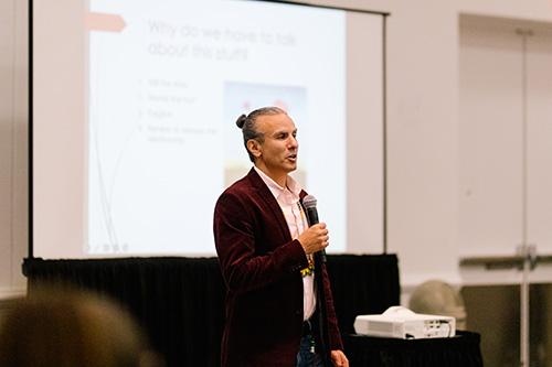 person holding a microphone at the front of a meeting room