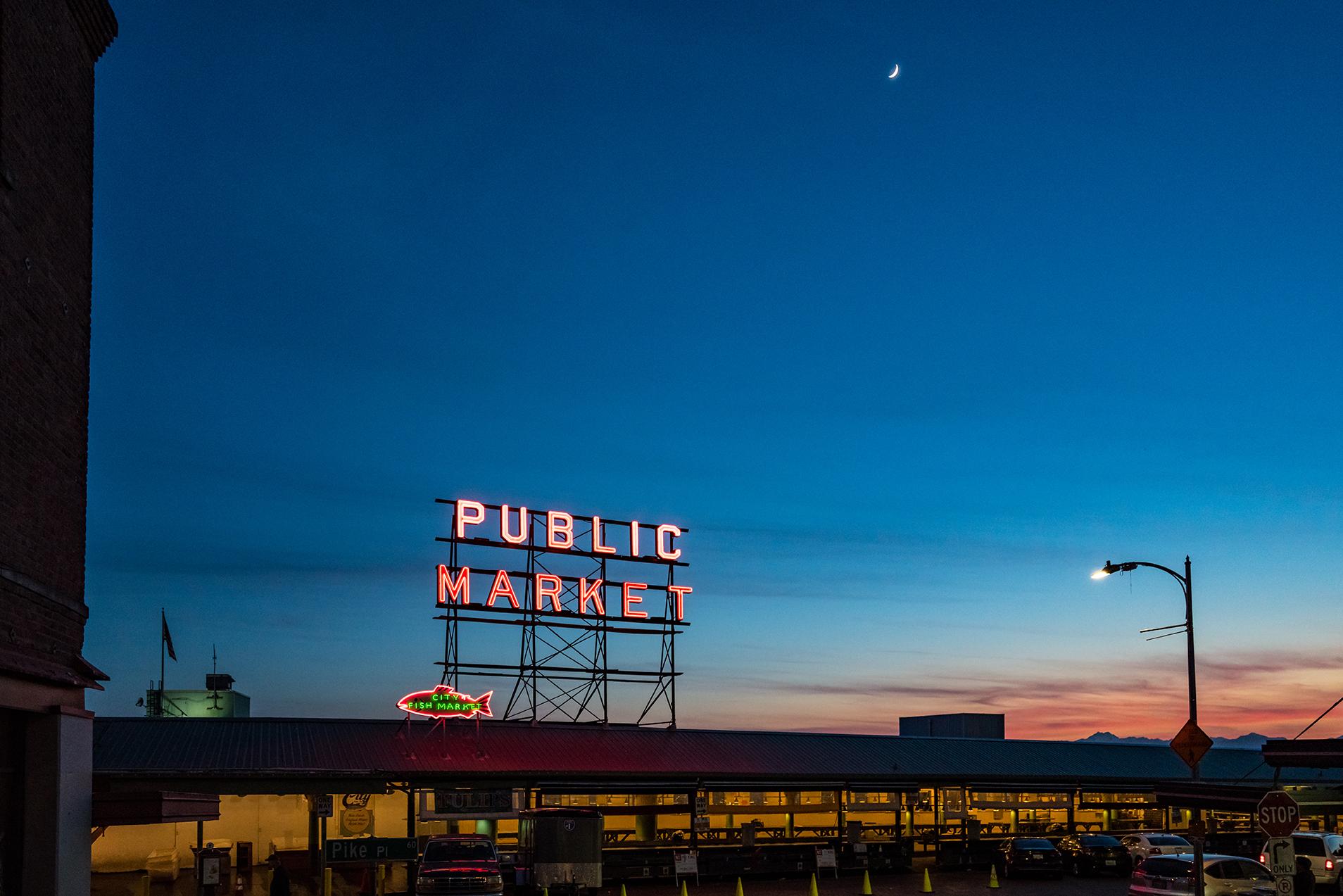 A sign above a building says, “public market" with a sunset in the background.