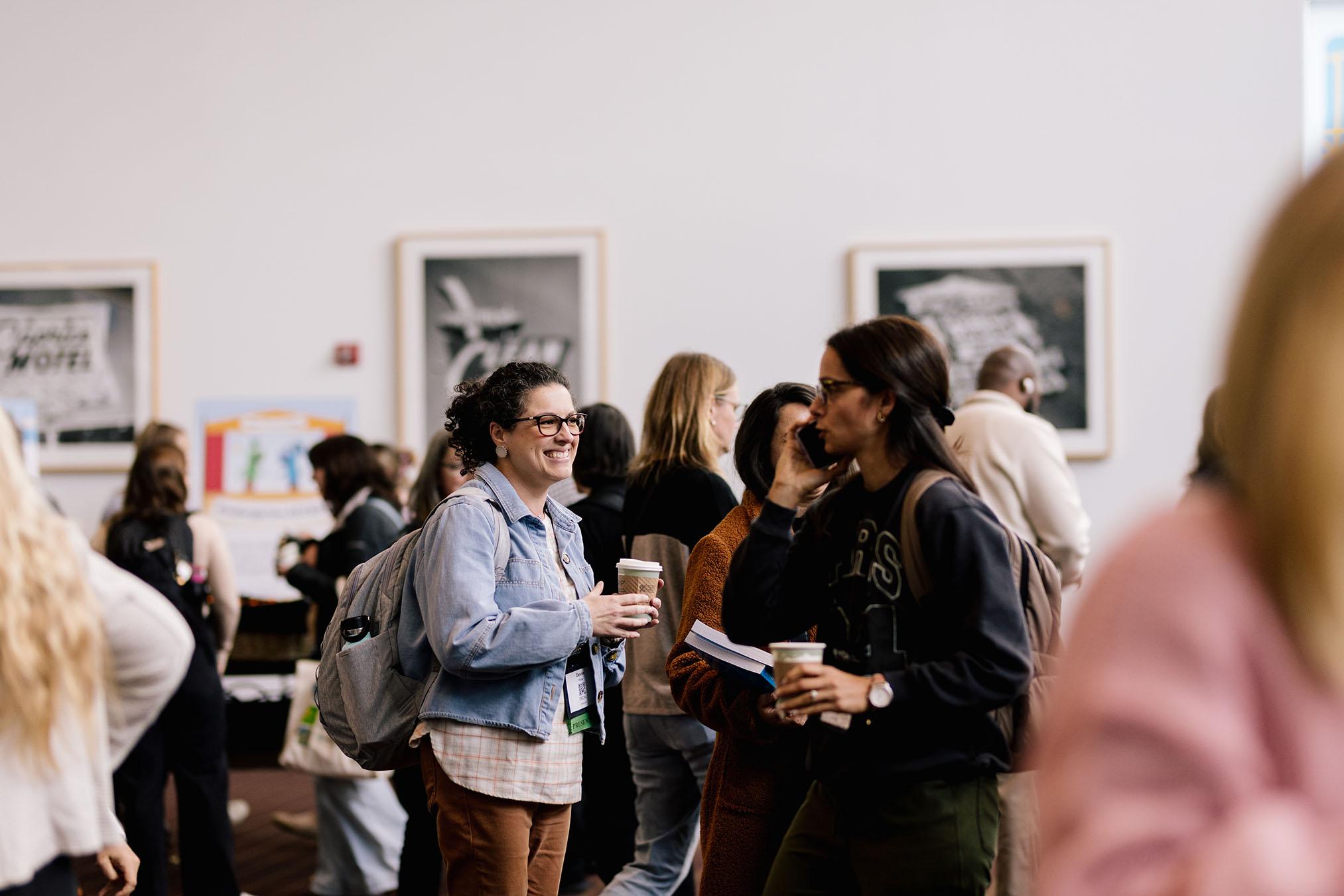 Two people holding coffee cups and smiling in a small crowd