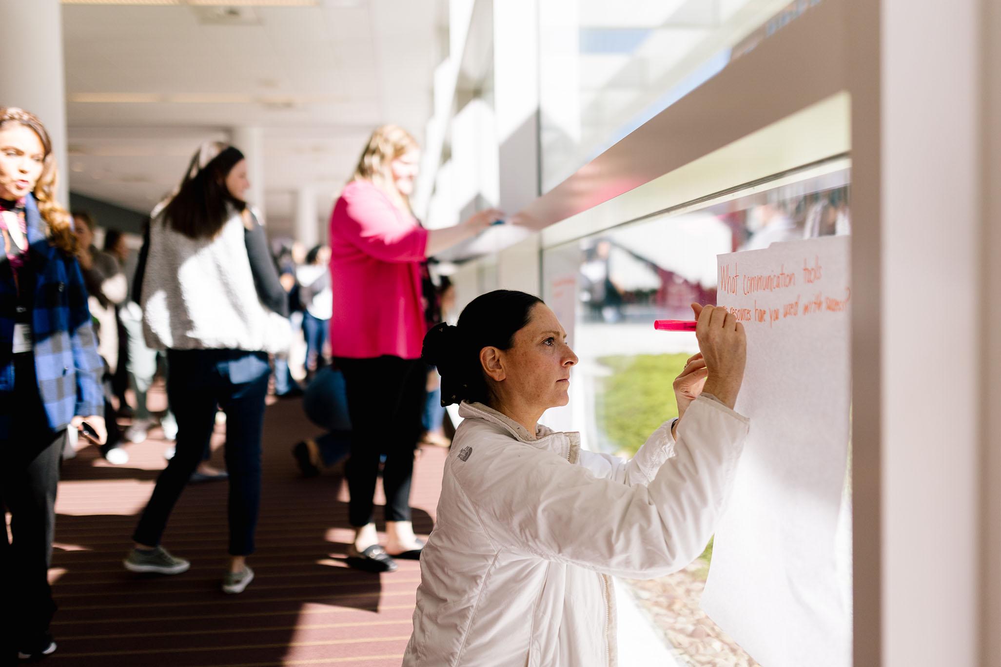 people writing on large pieces of paper that is adhered to a window